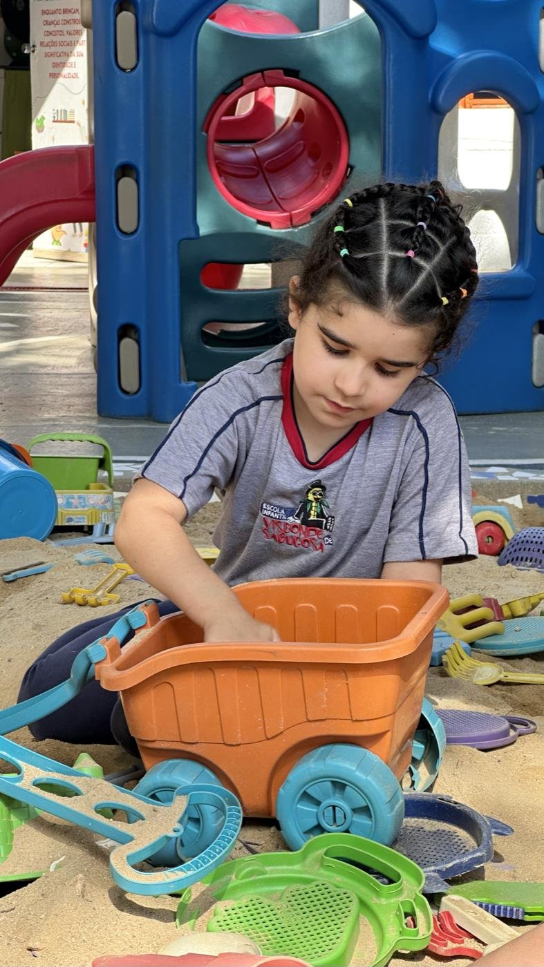Menina brincando com baldinho no parque de areia