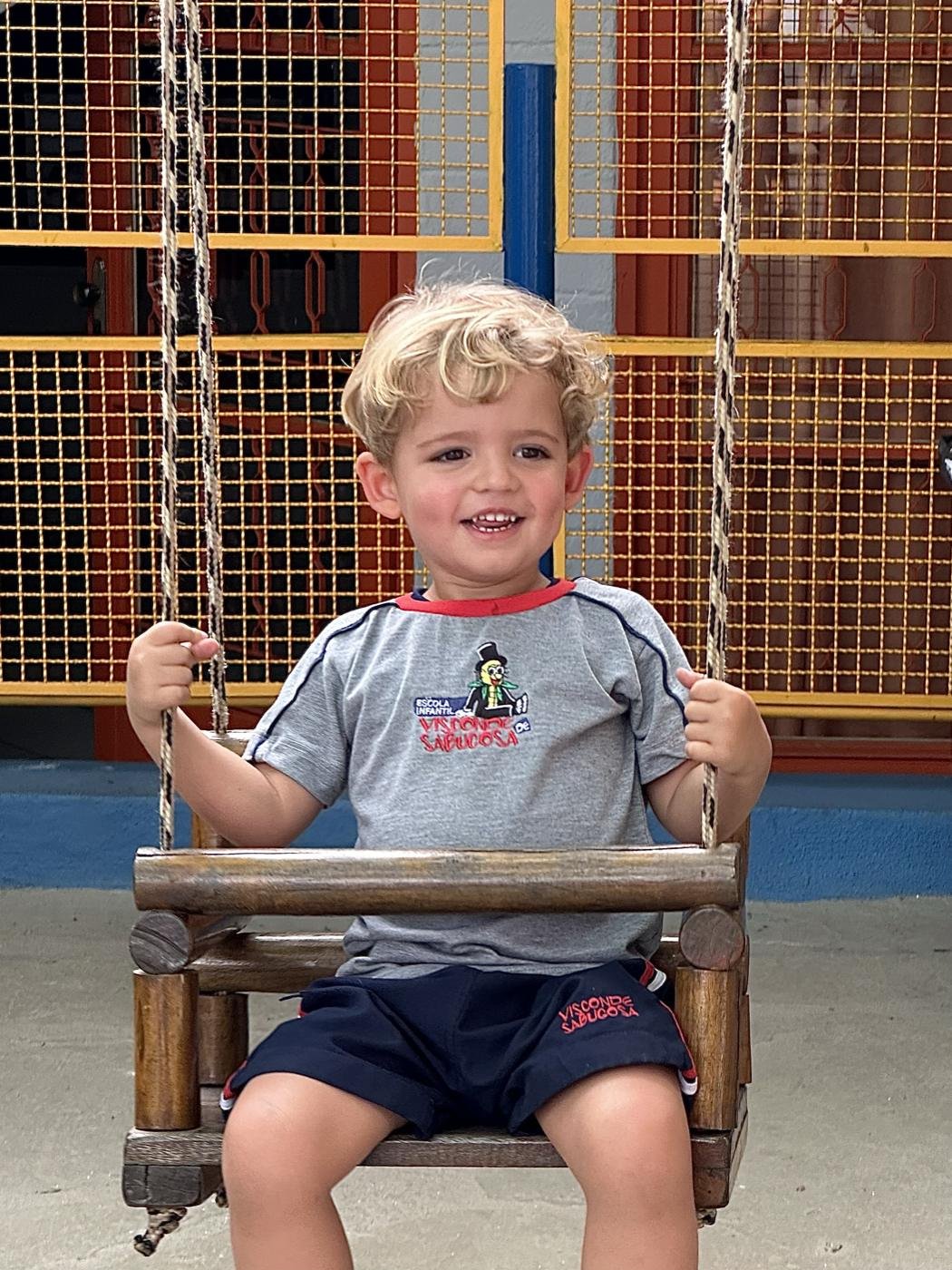 Menino sorrindo no balanço do pátio da escola